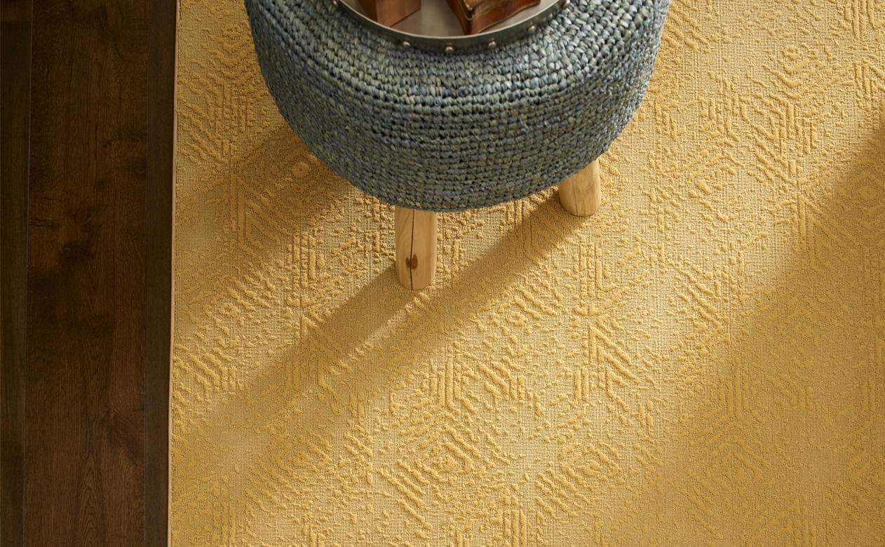 yellow textured area rug over wood-look flooring